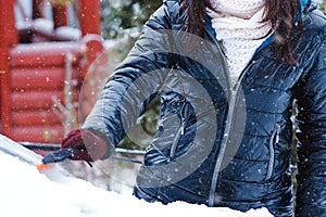 Man cleaning snow from car windshield with brush, close up. Woman removing snow from car. Snowy winter weather. Car in snow after