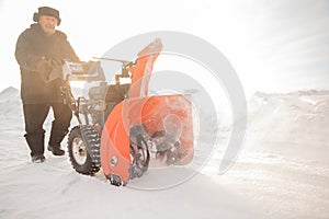 Man cleaning snow from thrower blower machine removal ice storm winter