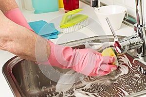 Man cleaning with a sponge and detergent a stainless steel sink