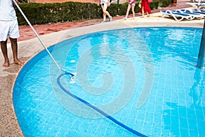 Man cleaning a swimming pool in summer. Cleaner of the swimming pool