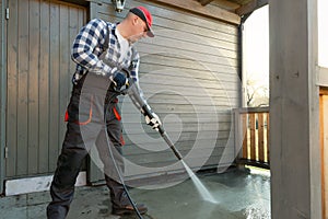 Man is cleaning terrace with a high temperature pressure cleaner on concrete terrace floor