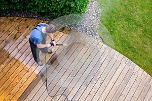 Man cleaning terrace with a power washer - high water pressure c