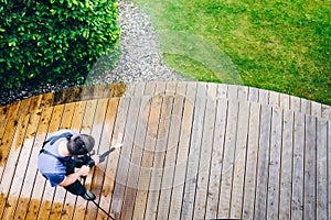 Man cleaning terrace with a power washer - high water pressure c