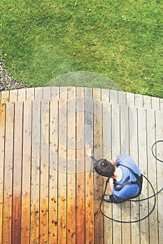 Man cleaning terrace with a power washer - high water pressure c