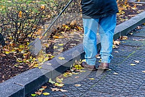 Man cleaning up fallen leaves with rake on sunny day, autumn work