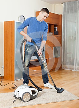 Man cleaning with vacuum cleaner in living room