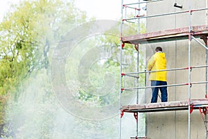 Man cleaning wall. Scaffolding