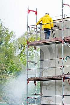 Man cleaning wall. Scaffolding