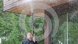 Man cleaning walls and floor with high pressure power washer. Washing terrace wood planks and cladding walls.