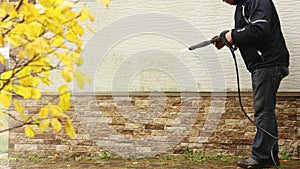 Man cleaning walls with high pressure power washer. Washing cladding walls house.