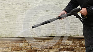 Man cleaning walls with high pressure power washer. Washing cladding walls house.