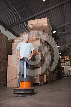 Man cleaning warehouse floor with machine