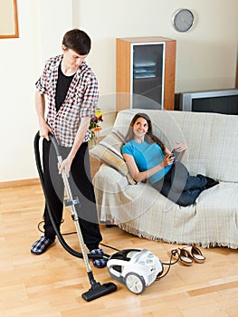 Man cleaning while wife lying with eBook