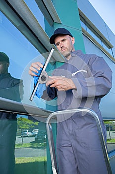 man cleaning windows with squeegee