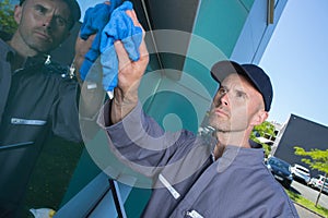 man cleaning windows with squeegee