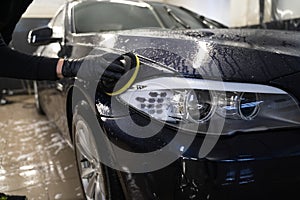 Man cleans car body with disc sponge. Preparing auto for polishing. .Detailed car wash.