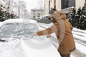 A man cleans a car of snow that has fallen overnight