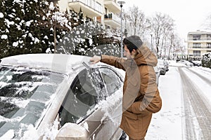 A man cleans a car of snow that has fallen overnight