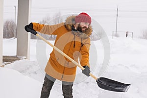 A man cleans and clears the snow in front of the house on frosty day. Cleaning the street from snow on a winter day