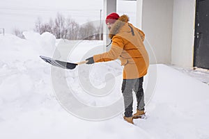 A man cleans and clears the snow in front of the house on frosty day. Cleaning the street from snow on a winter day