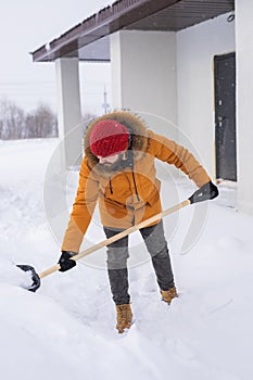 A man cleans and clears the snow in front of the house on frosty day. Cleaning the street from snow on a winter day