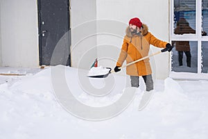 A man cleans and clears the snow in front of the house on frosty day. Cleaning the street from snow on a winter day