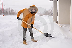 A man cleans and clears the snow in front of the house on frosty day. Cleaning the street from snow on a winter day