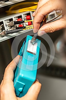 A man cleans the fiber optic cable connectors with a special blue cleaner. Cleaning connectors close up against the