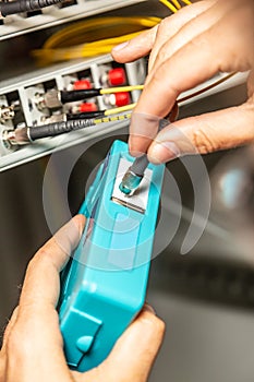 A man cleans the fiber optic cable connectors with a special blue cleaner. Cleaning connectors close up against the