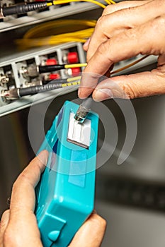 A man cleans the fiber optic cable connectors with a special blue cleaner. Cleaning connectors close up against the