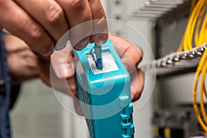 A man cleans the fiber optic cable connectors with a special blue cleaner. Cleaning connectors close up. Horizontal