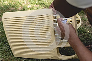 A man cleans the front grille of a window type air conditioner with a washrag and soap outside. Aircon cleaning service photo