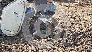 Man cleans knives or harrows ploughshares garden tillers from the stuck soil