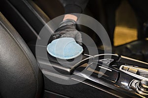 Man cleans leather armrest of car. Professional detailing.