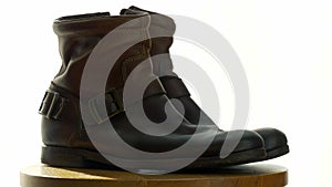 A man cleans old shoes on a wooden chair with a Shoe brush to wash away dust and dirt.