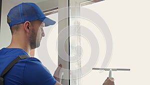 Man cleans plastic window glass with detergent and squeegee