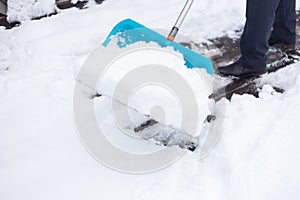 A man cleans the snow with a big blue shovel