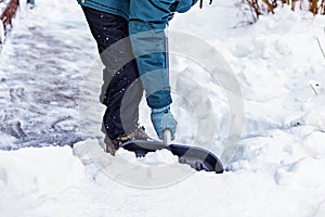 A man cleans the snow near the house with a big black shovel.