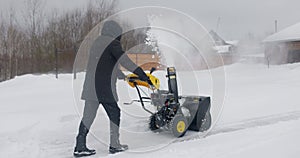 Man Cleans Snow With Snow Plow Background Of Wooden House after Heavy Snowfall. Snowplough in work. Slow motion