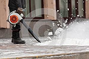 Man cleans street from snow with blower