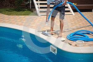 A man cleans a swimming pool with a hose with a brush, personnel