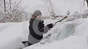 Man cleans windshield of car with brush from snow, son run, take scraper