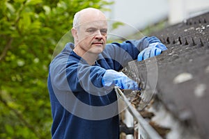Man Clearing Leaves From Guttering Of House