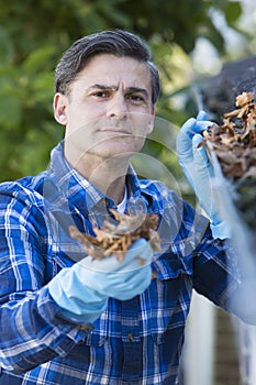 Man Clearing Leaves From Guttering Of House