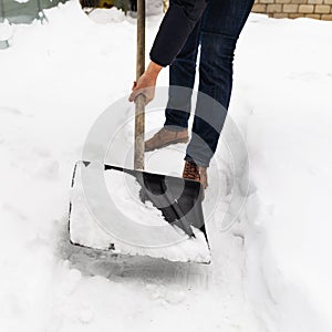 A man clears snow from paths on his property with a shovel