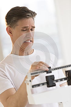 Man Clenching Teeth While Using Balance Weight Scale photo