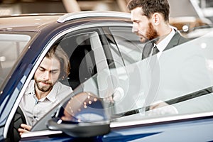 Man client with salesperson choosing car in the showroom