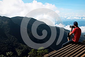 Man on the cliff edge photographing nature.