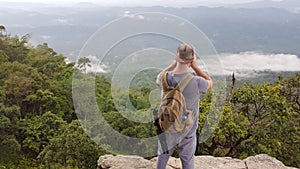 Man solo traveler and adventurer professional landscape photographer on a cliff photographing the valley and jungle