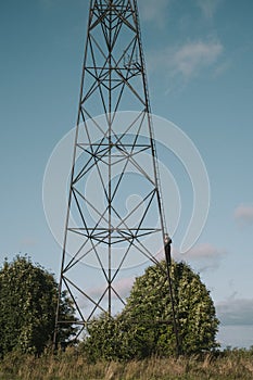 A man climbed a high transmitting radio antenna in a field. Silhouette of a man on a tall structure in a field